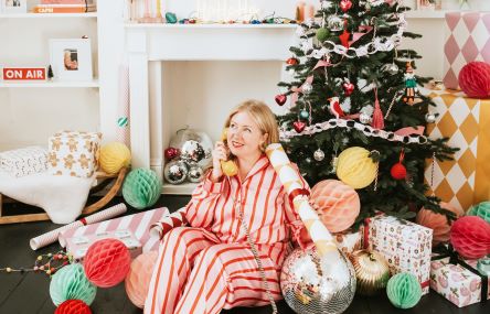 woman in pyjamas by a Christmas tree